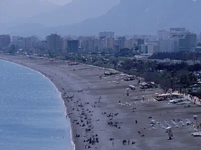 Konyaaltı Beach and Taurus mountains on May. You can find many either sea events or restaurants and bars behind of sand.